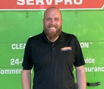 SERVPRO employee in front of green shrub